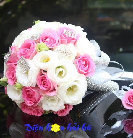 Bó hoa cưới cầm tay cô dâu hồng cánh sen và cát tường trắng
